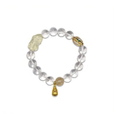 Clear Quartz beaded bracelet featuring a carved yellow wealth charm and gold accent on white background.