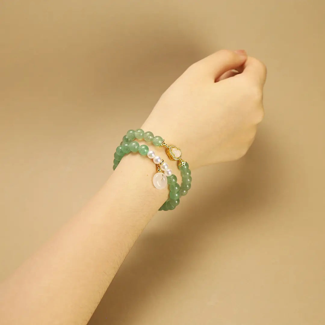 Woman wearing a double-layer Green Quartz bracelet on wrist, showing the elegant fit and pearl accents.