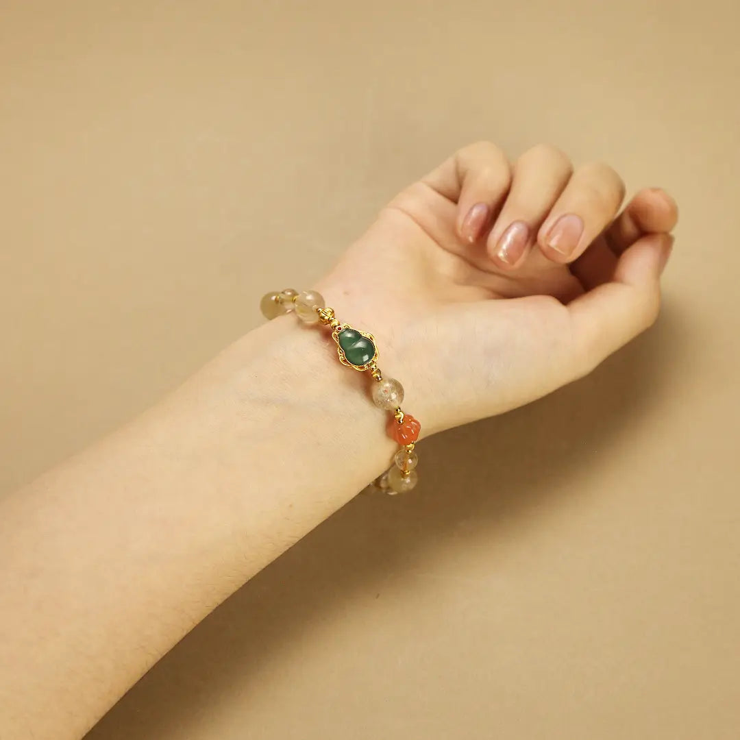 Woman wearing a Feng Shui wealth bracelet on wrist, showing the Jade Hulu charm for protection.